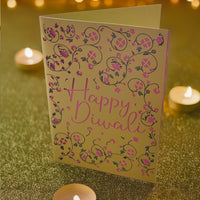 Handmade Happy Diwali greeting card with intricate pink floral cut-out design on gold cardstock, styled with festive fairy lights.
