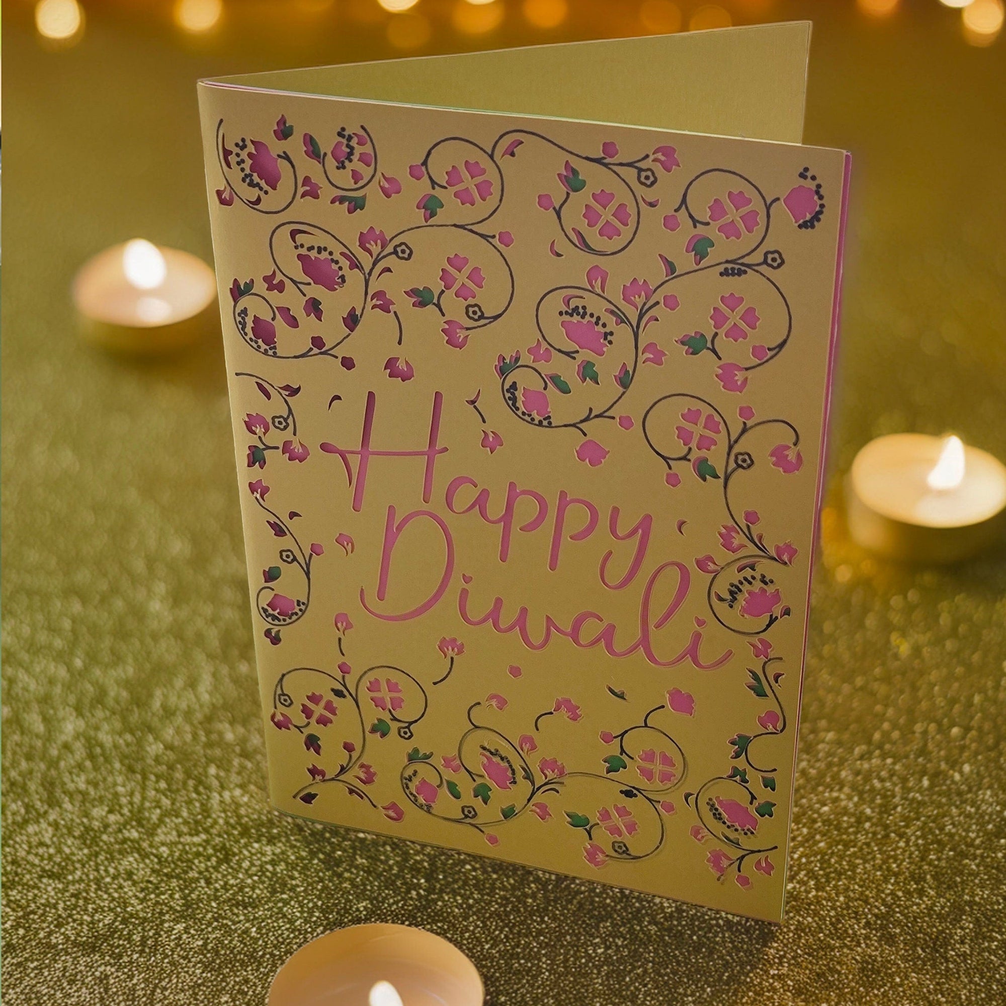 Handmade Happy Diwali greeting card with intricate pink floral cut-out design on gold cardstock, styled with festive fairy lights.