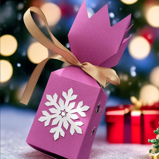 Handmade pink Christmas cracker box with snowflake design and gold ribbon, perfect for festive celebrations.