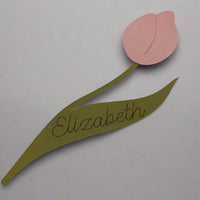Handmade tulip-shaped place card in pink and green cardstock with the name “Elizabeth” on the leaf, laid flat on a plain background.