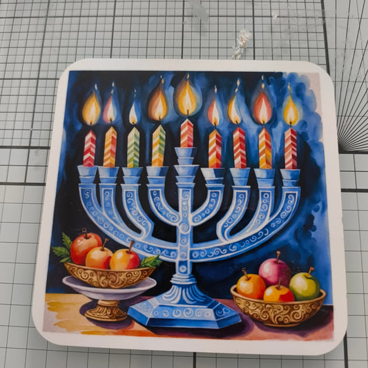Hanukkah coaster with menorah and nine colourful lit candles, with fruit bowls, close-up view