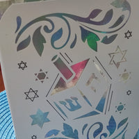 Hanukkah greeting card with dreidel cut-out and holographic silver-blue background on table