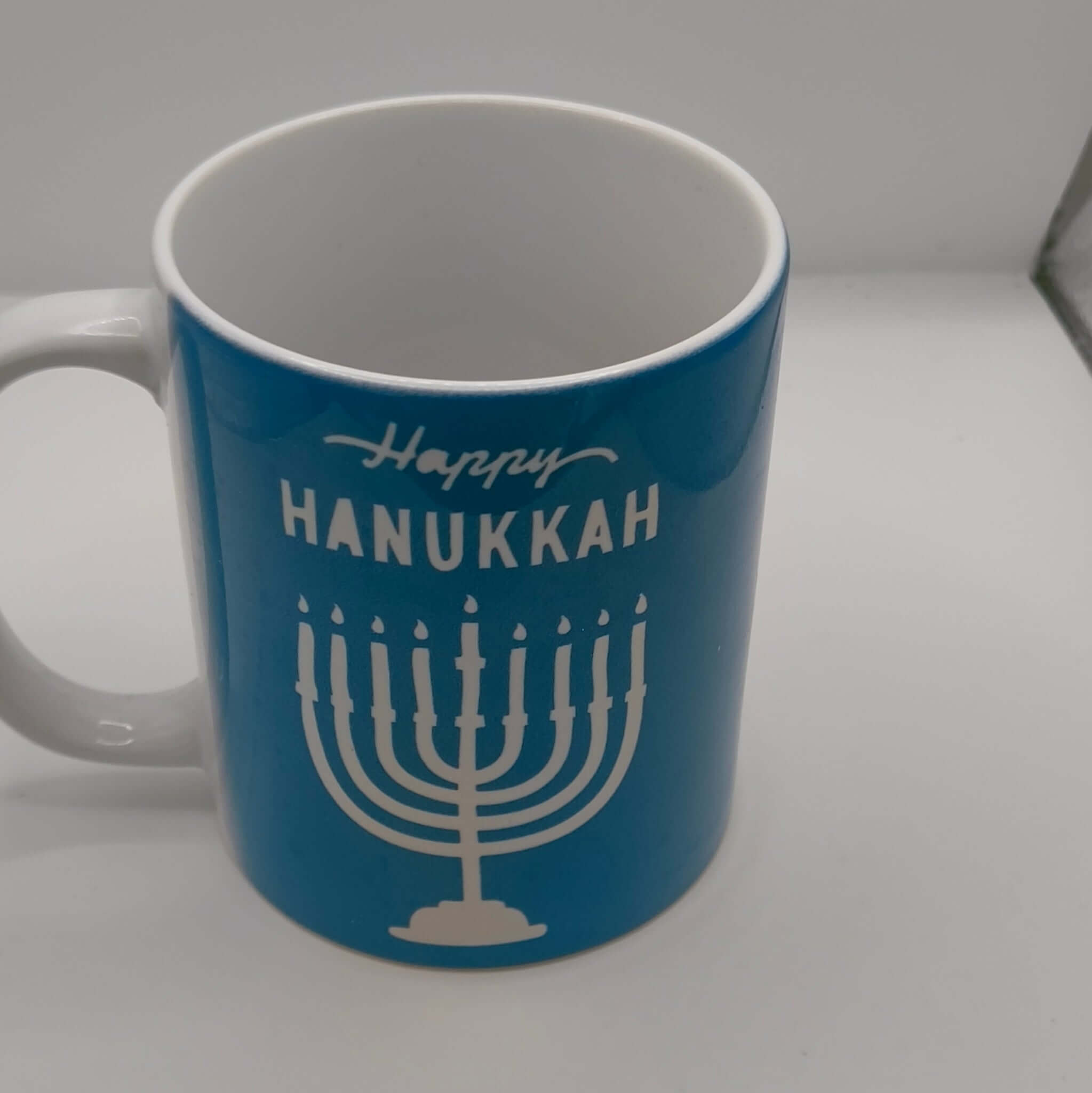 Happy Hanukkah mug featuring a blue design with a menorah and festive lettering.