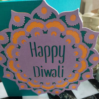 Close-up of “Happy Diwali” cut-out with layered mandala. Purple, gold, and teal cardstock textures visible, showcasing craftsmanship.