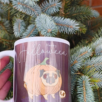 Happy Halloween mug featuring a cute pug dressed as a pumpkin on a dark purple background, perfect spooky season gift for dog lovers.