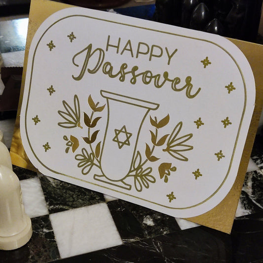Elegant white card with gold foil “Happy Passover” design, featuring a Star of David goblet and floral motifs. Photographed upright to show full scale and shine.