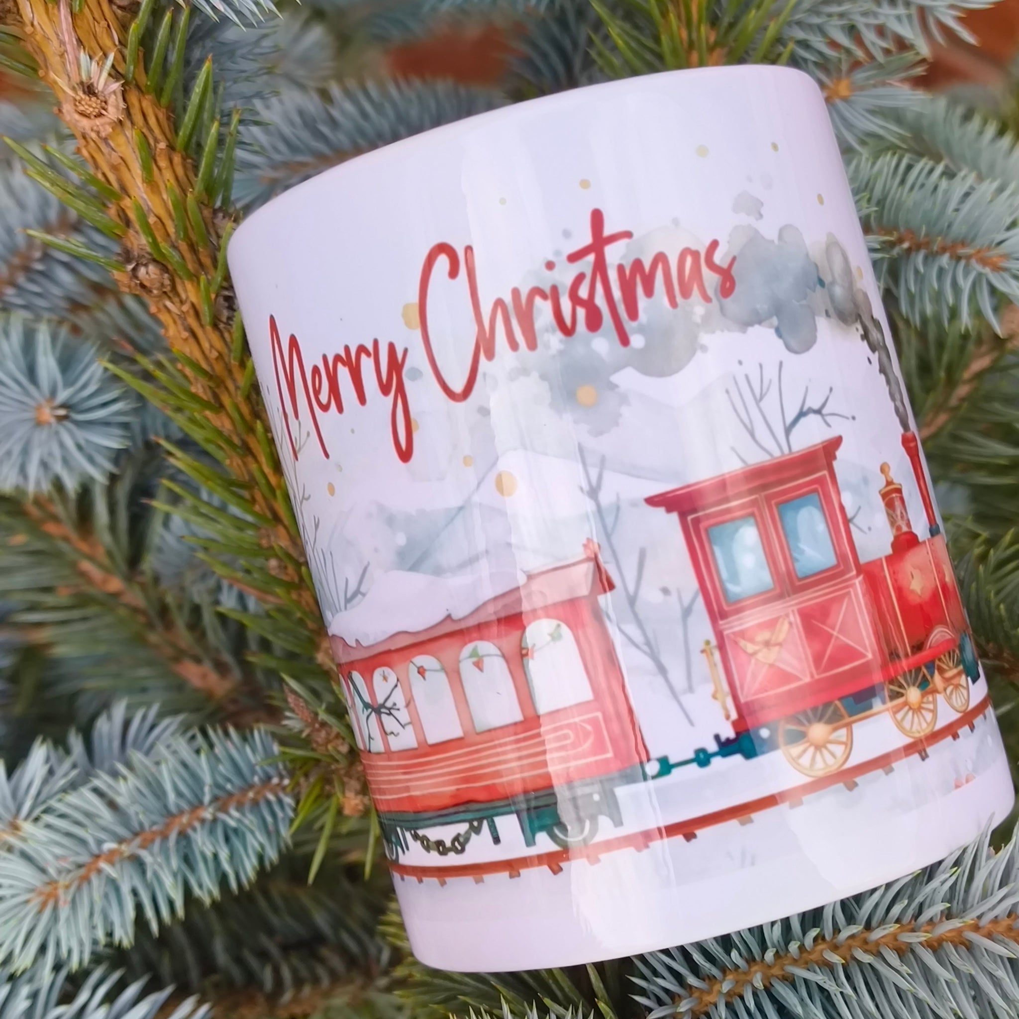 Holiday mug with red train and winter forest artwork displayed on tree