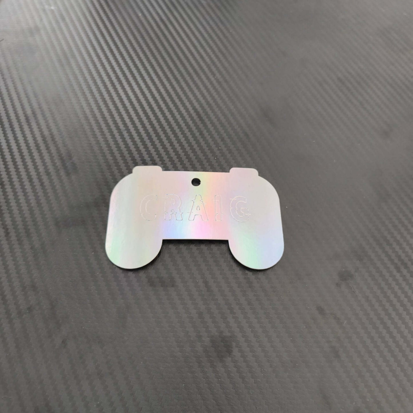 Personalised holographic gaming gift tag shaped like a game controller with the name 'CRAIG'