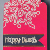 Close-up of black and gold Happy Diwali label on textured cardstock with elegant floral detail above