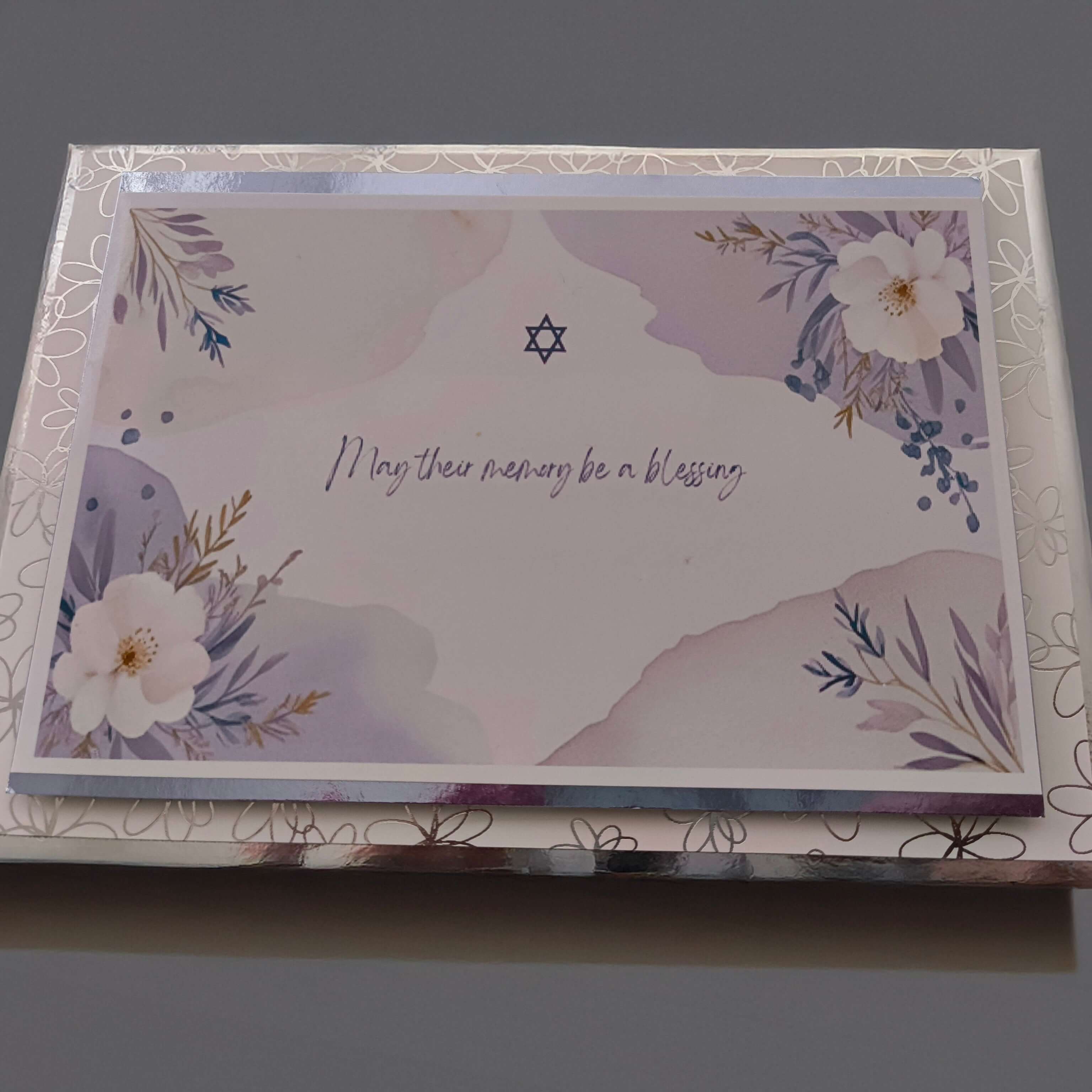 Jewish condolence card with Star of David and floral design, message reads 'May their memory be a blessing', shown with matching envelope