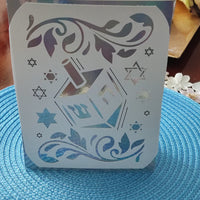 Jewish festival card with dreidel and floral cut-out pattern, holographic detail