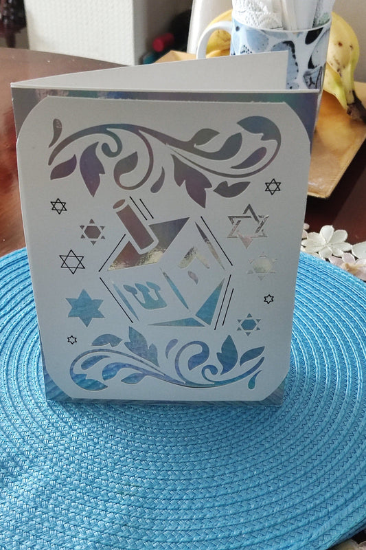 Jewish festival card with dreidel and floral cut-out pattern, holographic detail