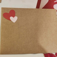 Kraft envelope decorated with two paper hearts in red and pink, matching the handmade love card design.