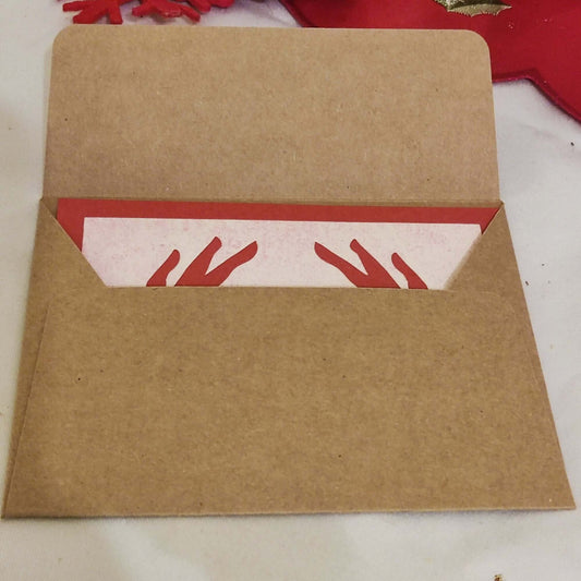 Kraft envelope partially open with handmade love card inside showing red heart hands design.