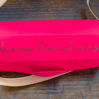 Personalised red Christmas cracker with glittery 'Merry Christmas' text and gold ribbon.