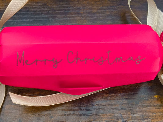Personalised red Christmas cracker with glittery 'Merry Christmas' text and gold ribbon.