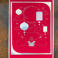 Handmade Mid-Autumn Festival card in red foil featuring moon rabbits, lanterns, and celestial designs.