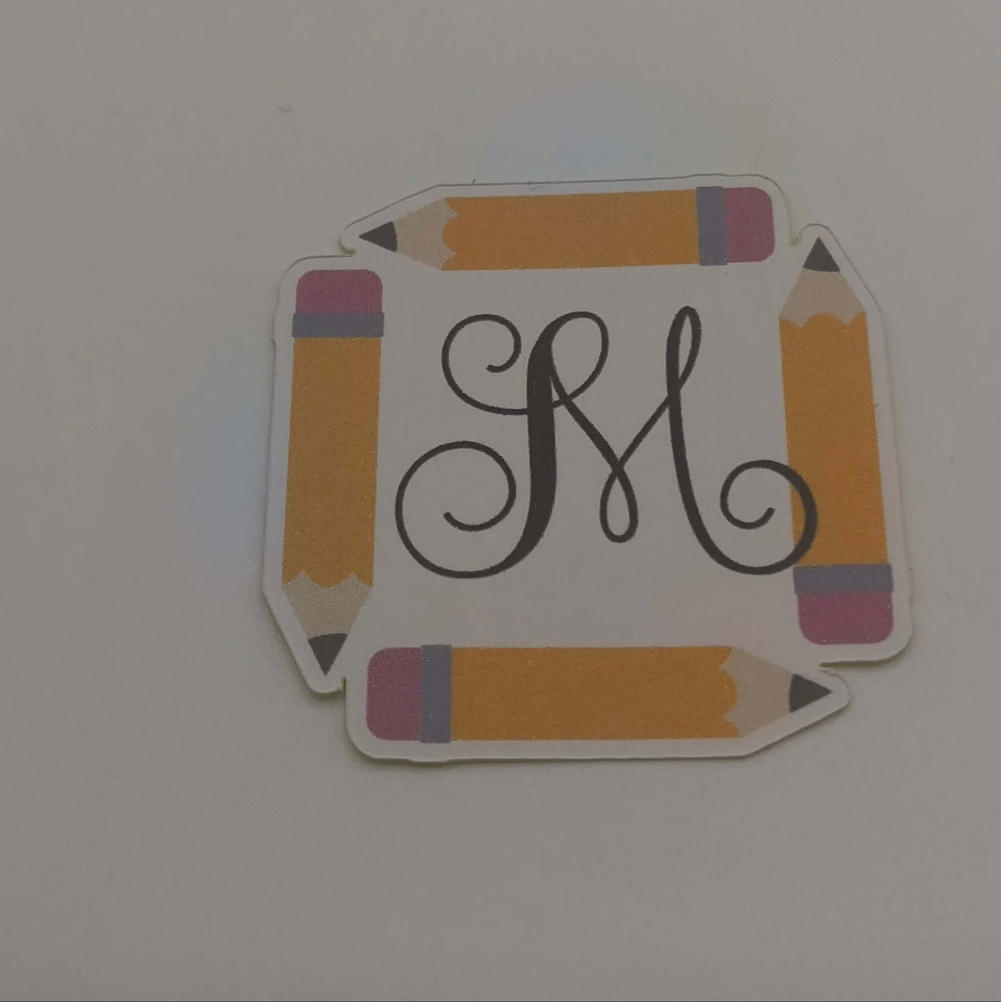 Personalised School Name Stickers featuring a decorative monogram framed by colorful pencil designs