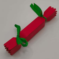 Reverse view of the cracker, tied at both ends with green ribbon. Shows clean folds, scalloped edging, and sturdy handmade finish.