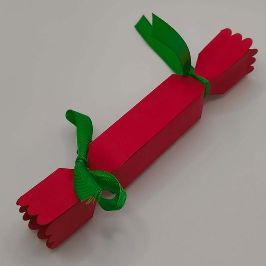 Reverse view of the cracker, tied at both ends with green ribbon. Shows clean folds, scalloped edging, and sturdy handmade finish.