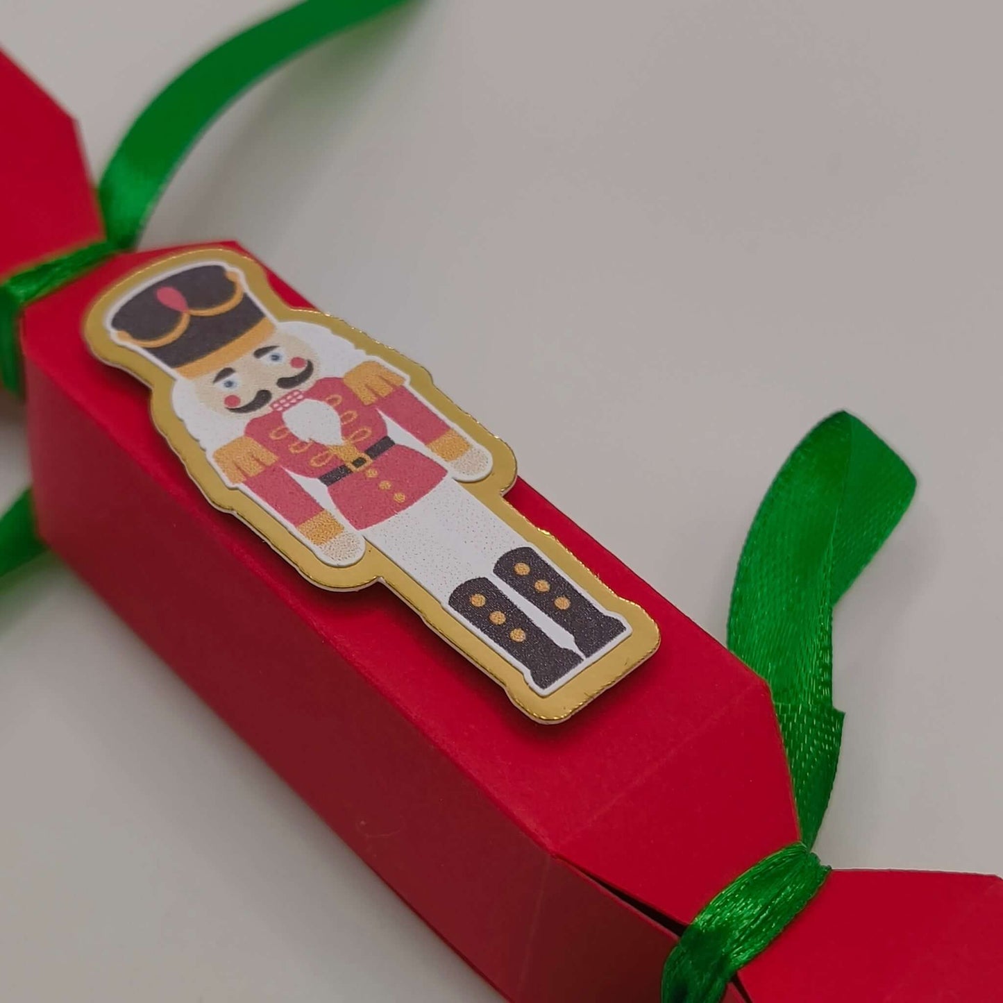 Close-up of the nutcracker detail, showing gold edging and printed design on textured cardstock. Crisp festive colours highlight the craftsmanship.