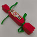 Handmade red Christmas cracker with green ribbon and nutcracker decoration. Festive and vibrant, sized for table settings or small gifts.