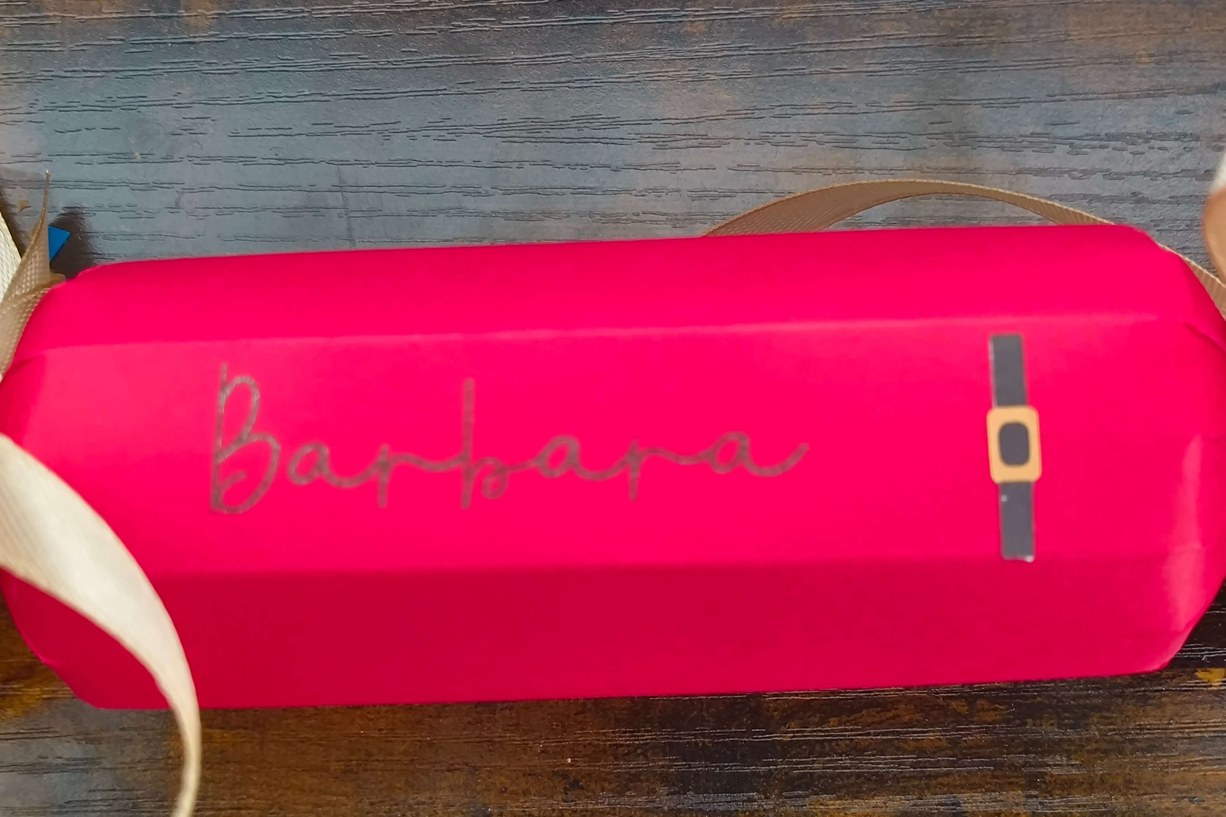 Personalized red Christmas cracker with gold ribbon and name 'Barbara' in festive handwriting.