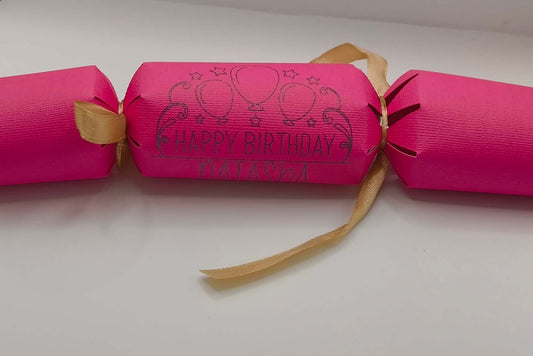 Personalised Birthday Crackers in vibrant pink with 'Happy Birthday' print and ribbon, perfect for celebrations.