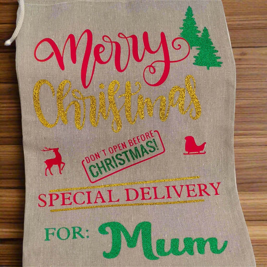 Personalised Christmas gift sack for Mum – hessian fabric with gold glitter “Christmas”, red festive icons, green vinyl name and trees, special delivery holiday design.