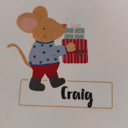 Close up of personalised Christmas coaster with mouse in spotty jumper holding wrapped presents and name Craig