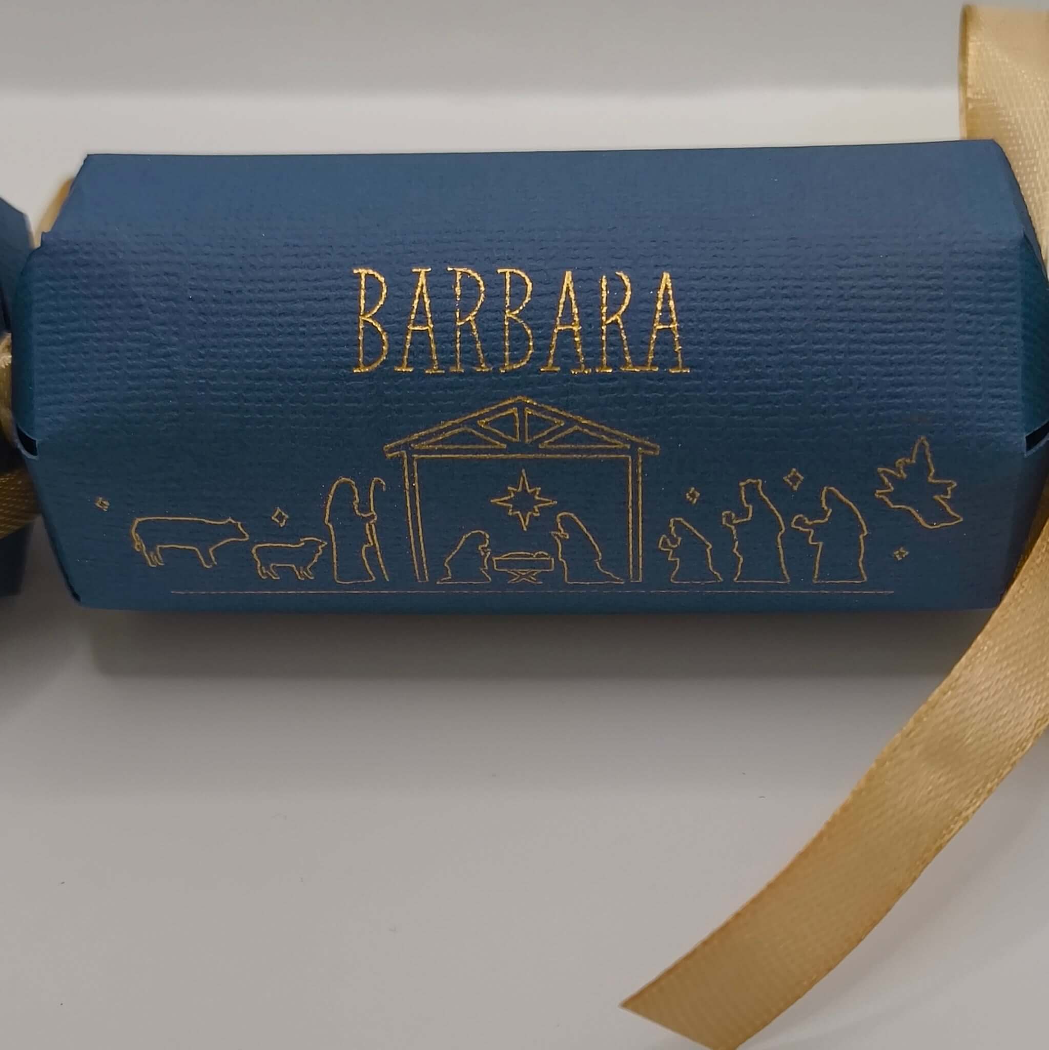 Close-up of navy blue Christmas cracker with gold foiled Nativity scene and personalised name ‘Barbara’ in elegant lettering