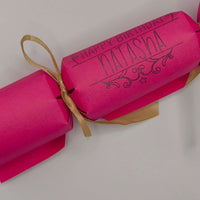 Personalised Birthday Crackers in pink with gold ribbon, perfect for celebrating special occasions.