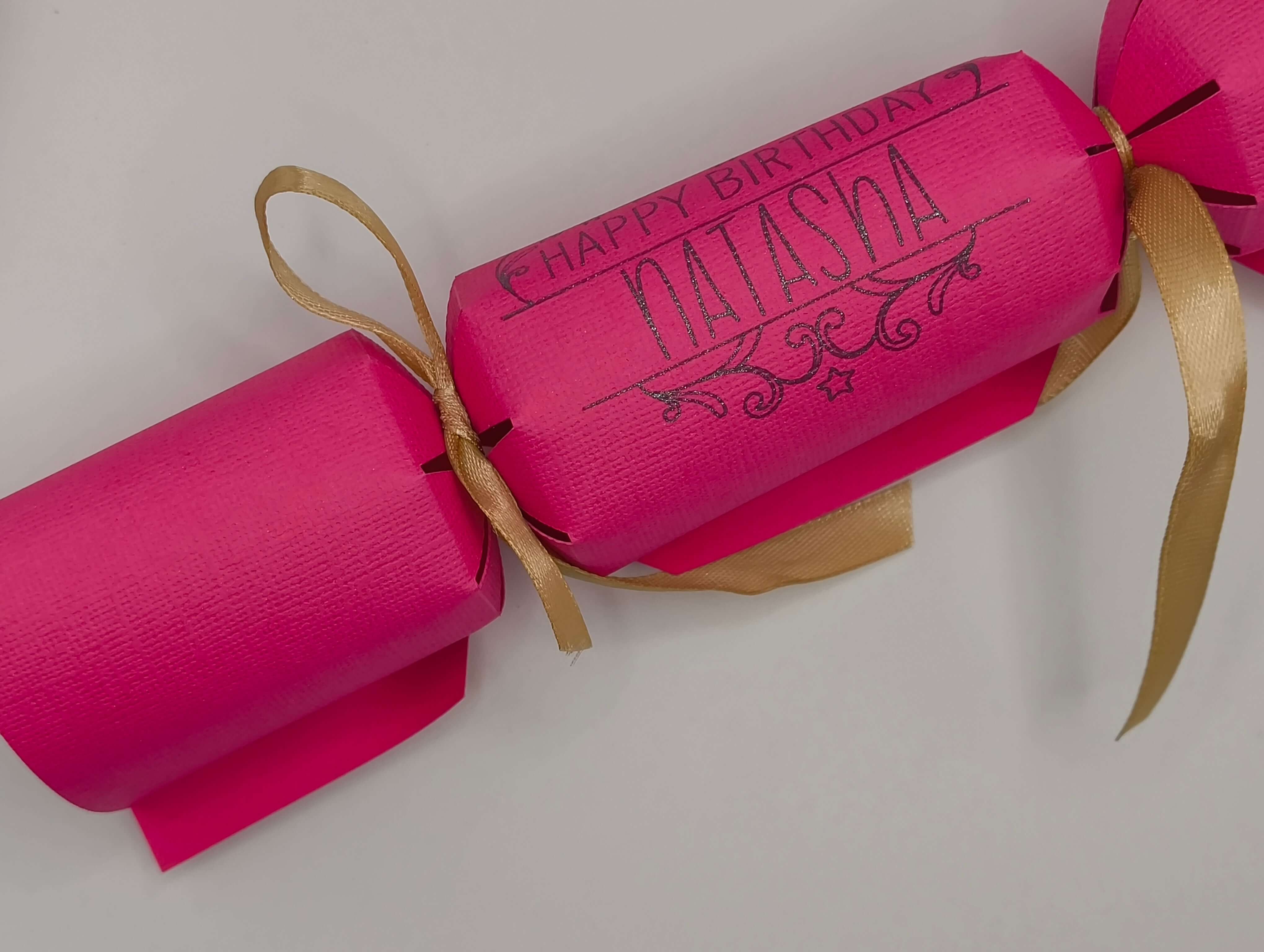 Personalised Birthday Crackers in pink with gold ribbon, perfect for celebrating special occasions.