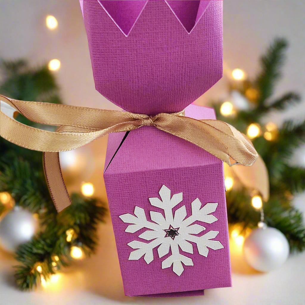Handmade pink Christmas cracker box with snowflake design and golden ribbon, perfect for holiday gifts.