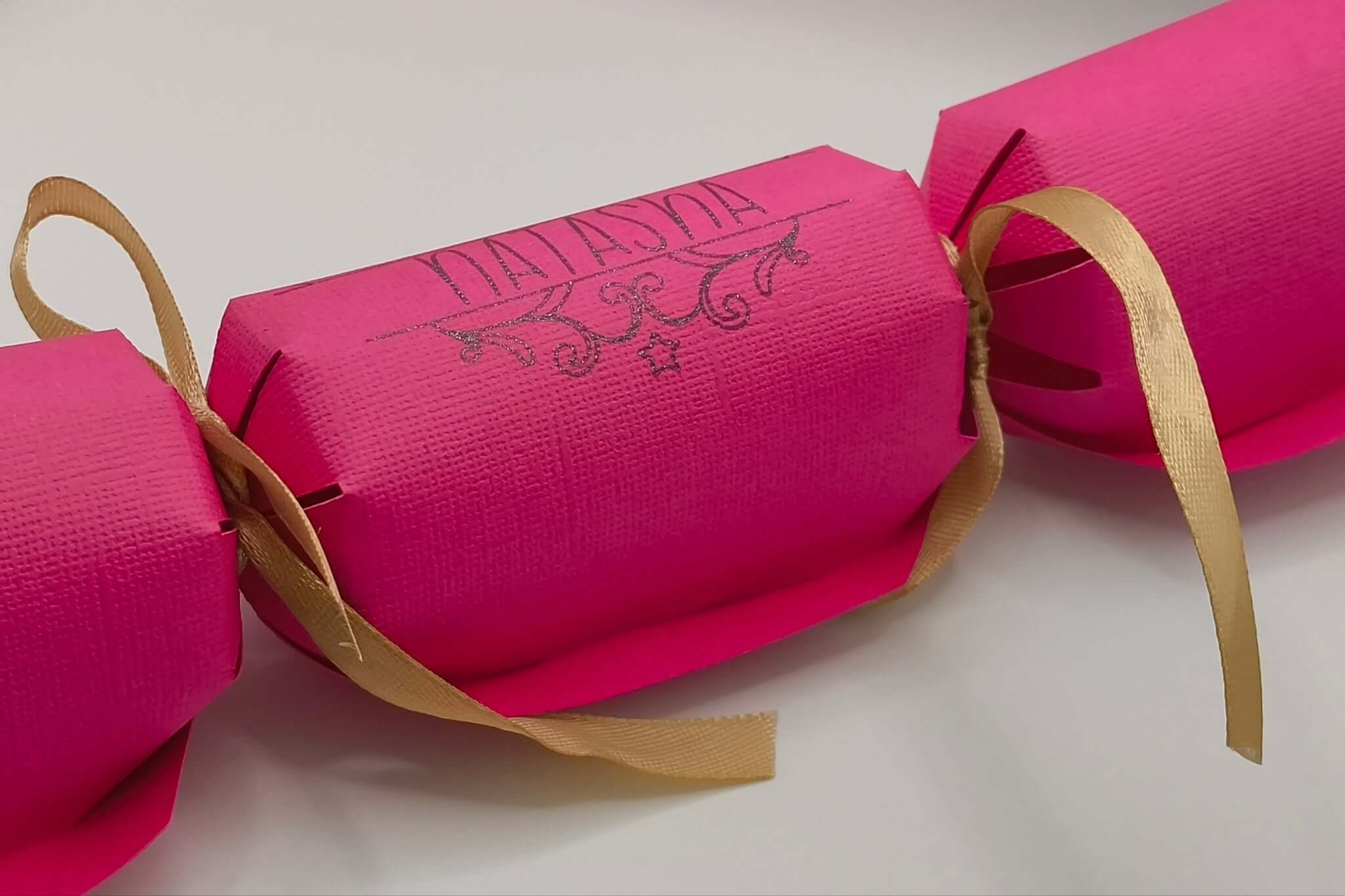 Personalised Birthday Crackers in vibrant pink with golden ribbon, perfect for celebrations.