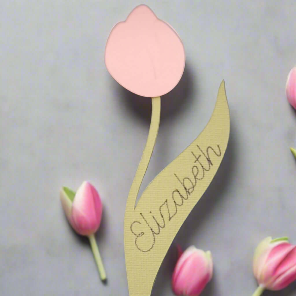 Pink tulip place card with personalised name “Elizabeth” written on the leaf, crafted from textured cardstock, displayed with small tulip buds.
