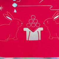 Handmade red foil card featuring two moon rabbits and a glowing lantern for Mid-Autumn Festival celebration.