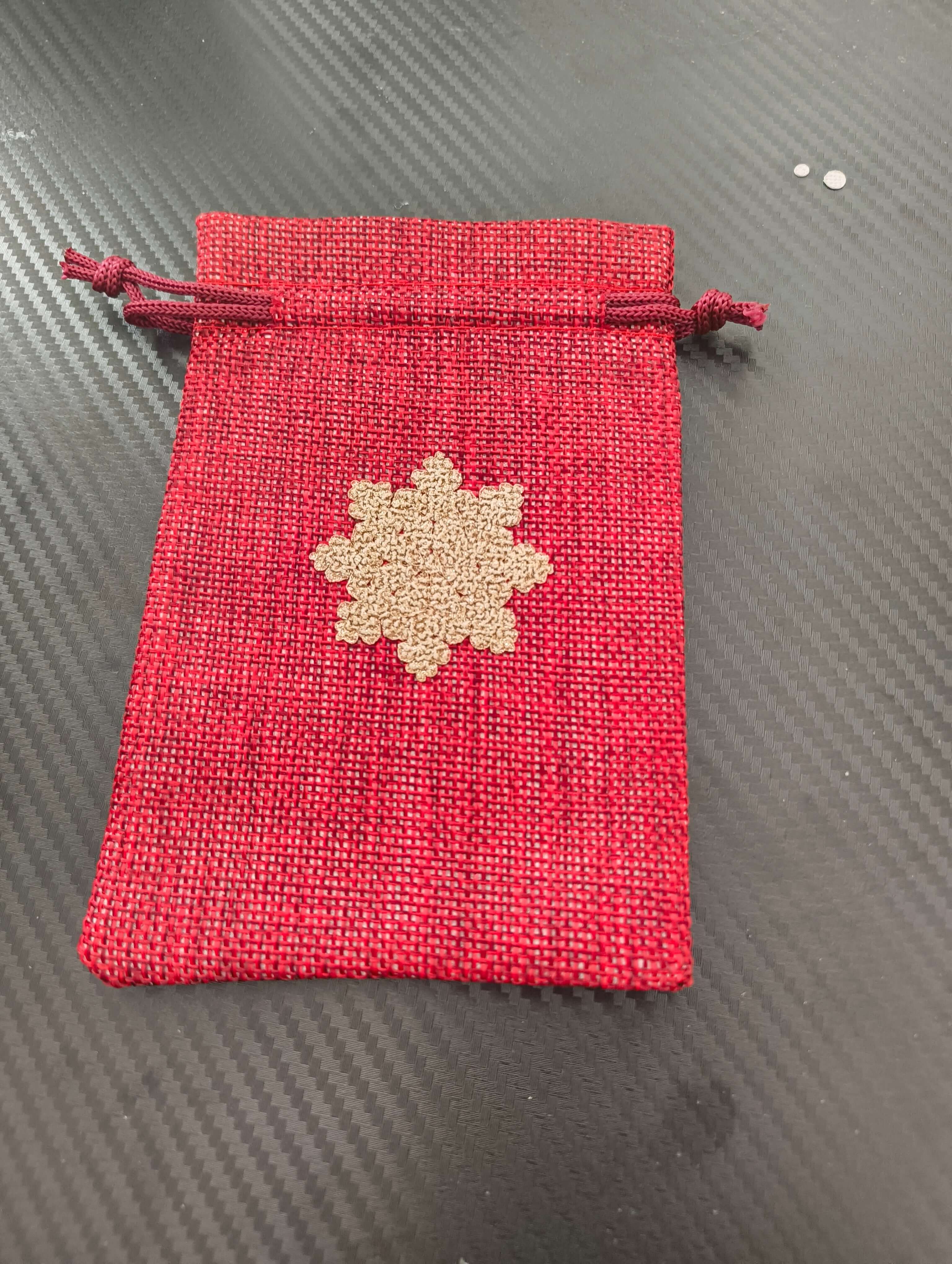 Red drawstring pouch gift bag featuring a golden snowflake, perfect for Christmas presents.