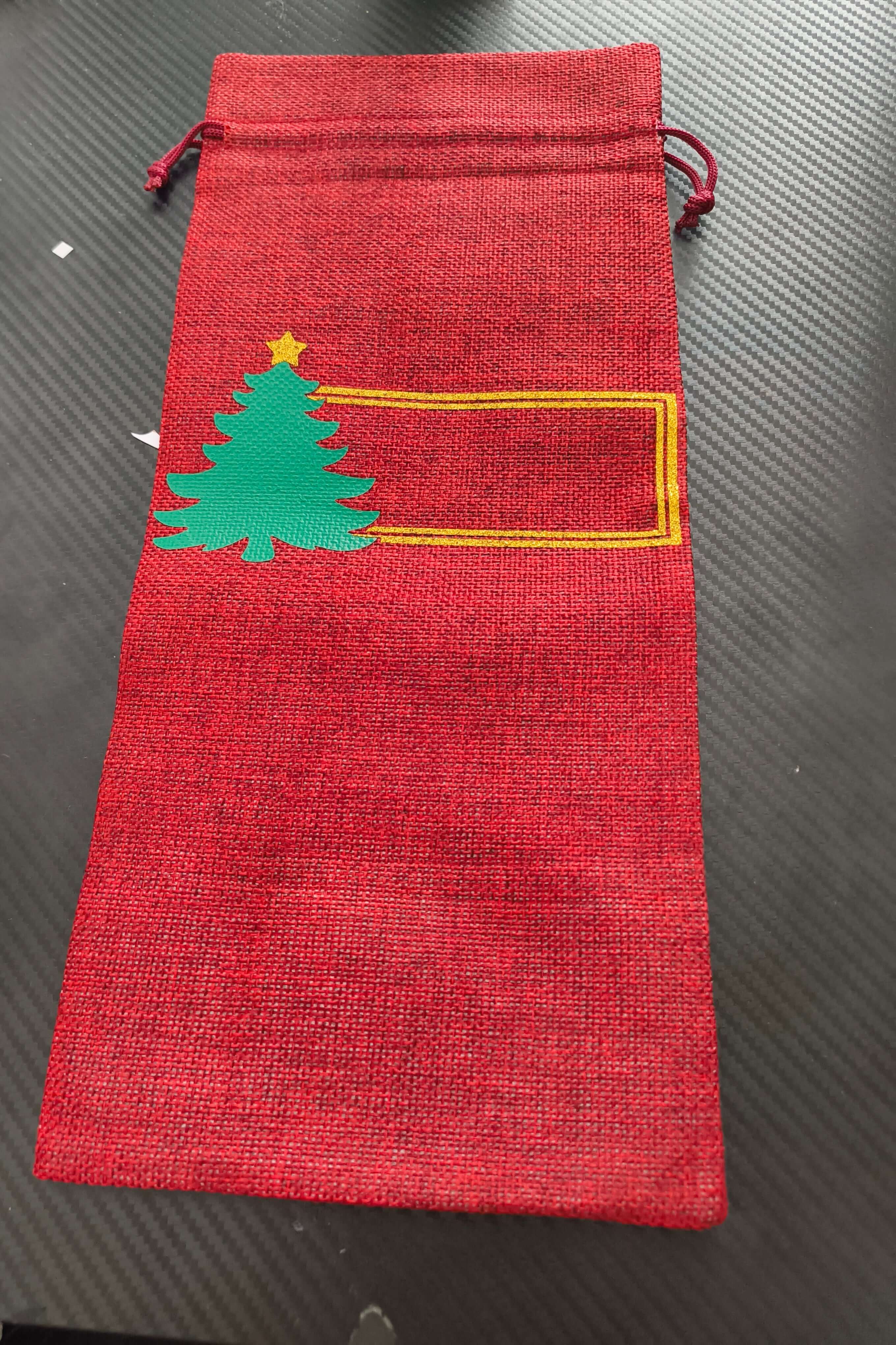 Personalised red hessian wine bottle bag with green Christmas tree and space for a name or message.