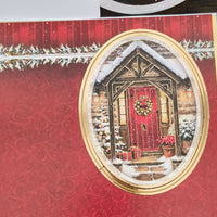 Handmade Christmas card base with gold border and red patterned background featuring snowy red door cottage design.