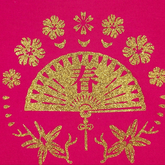 Glittering gold fan and floral pattern on a red fabric tote bag, captured in detailed close-up.