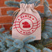 Santa Mail drawstring hessian gift bag hanging on outdoor Christmas tree against brick wall.