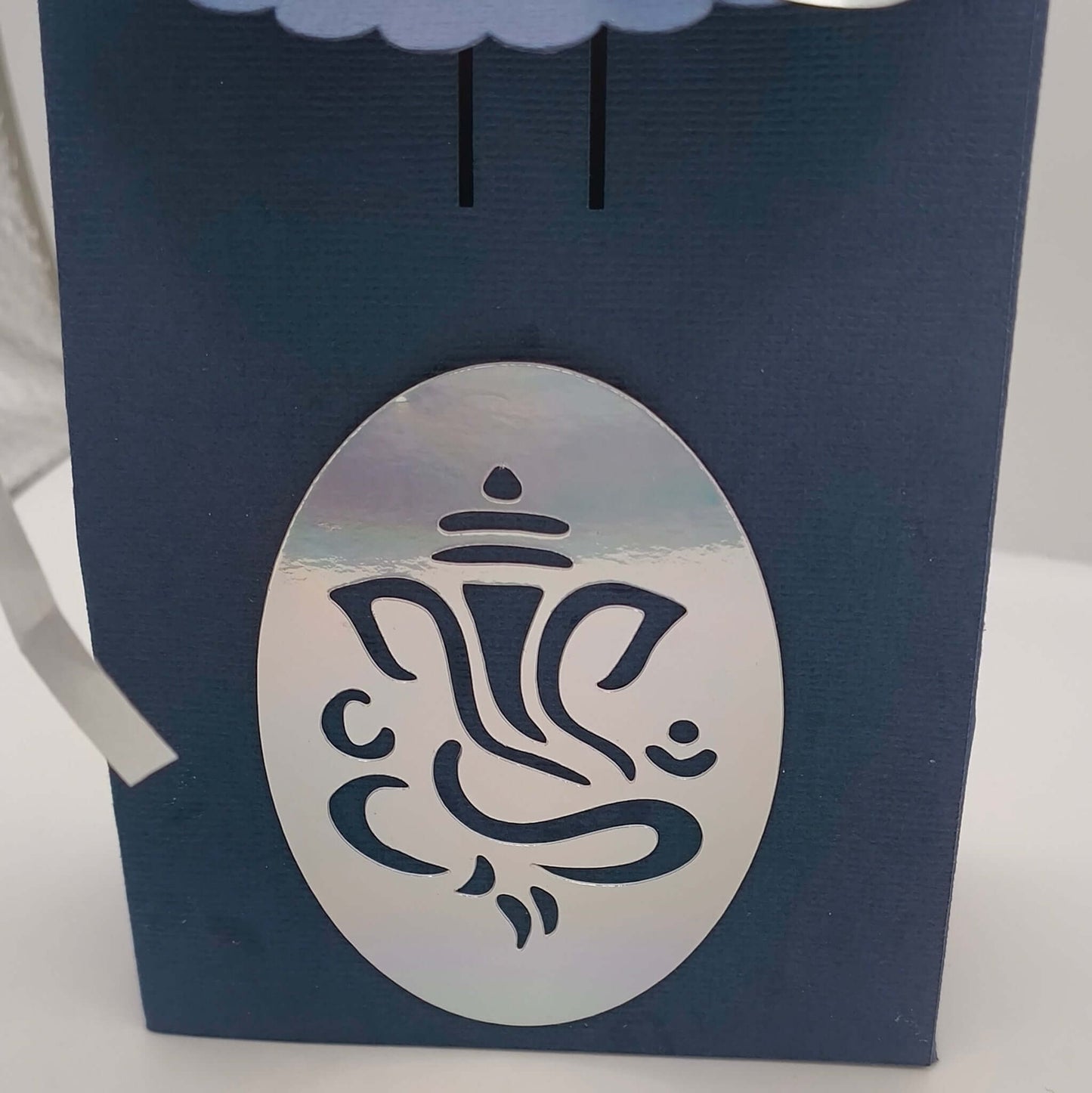 Close-up of silver Ganesh motif on navy blue Hindu gift box, perfect for Diwali, wedding favours, or festive gifting.