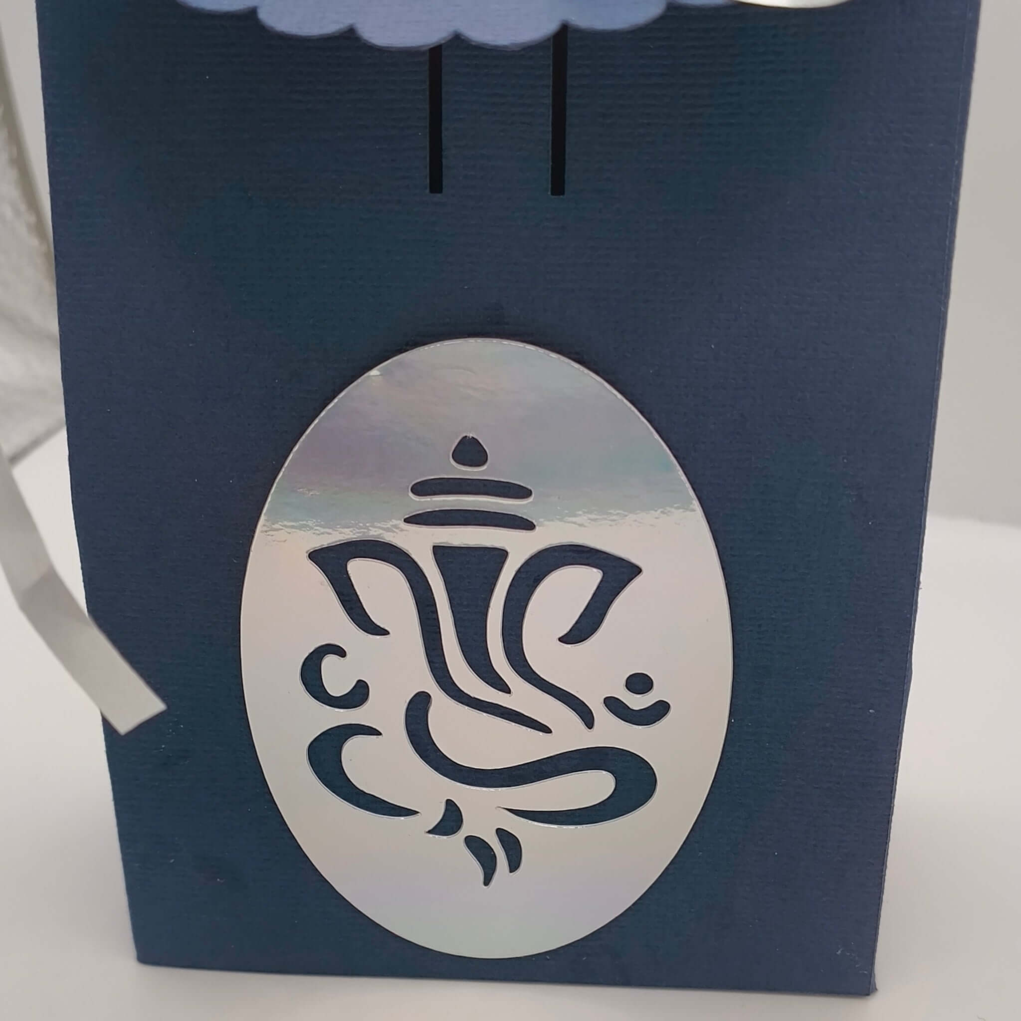 Close-up of silver Ganesh motif on navy blue Hindu gift box, perfect for Diwali, wedding favours, or festive gifting.
