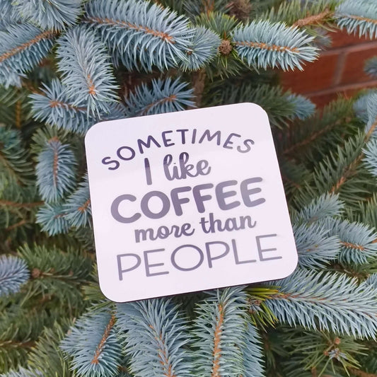 Funny coffee coaster gift with the phrase 'Sometimes I like coffee more than people' on a pine tree background.