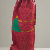 Personalised Christmas wine bottle bag in red hessian with green tree design, perfect for festive gifting.