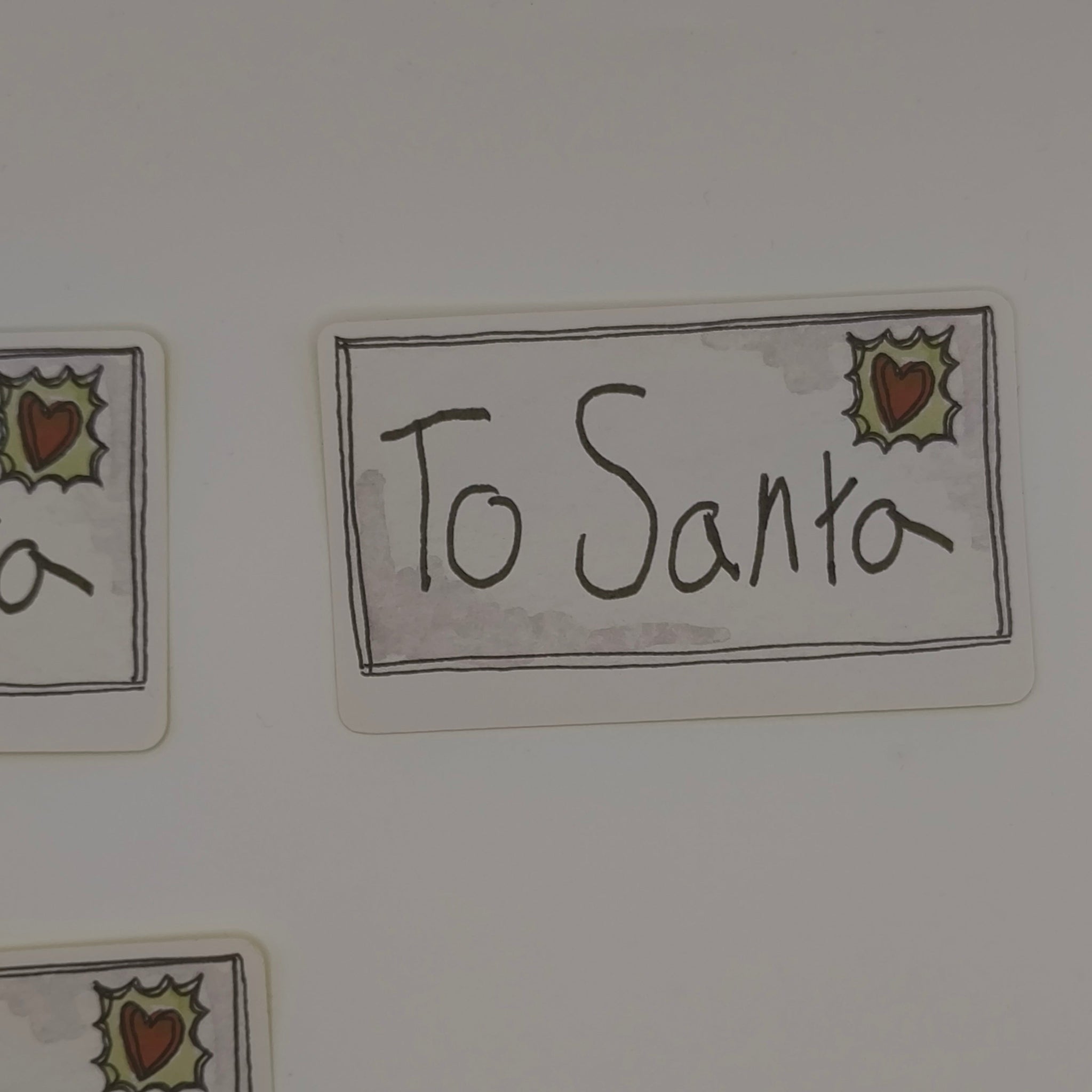 Close-up of To Santa sticker with holly and heart design, festive label style