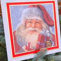 Close-up of a traditional Father Christmas Advent Calendar with numbered doors, featuring a vintage-style Santa holding a red present, displayed on a blue spruce tree outdoors.