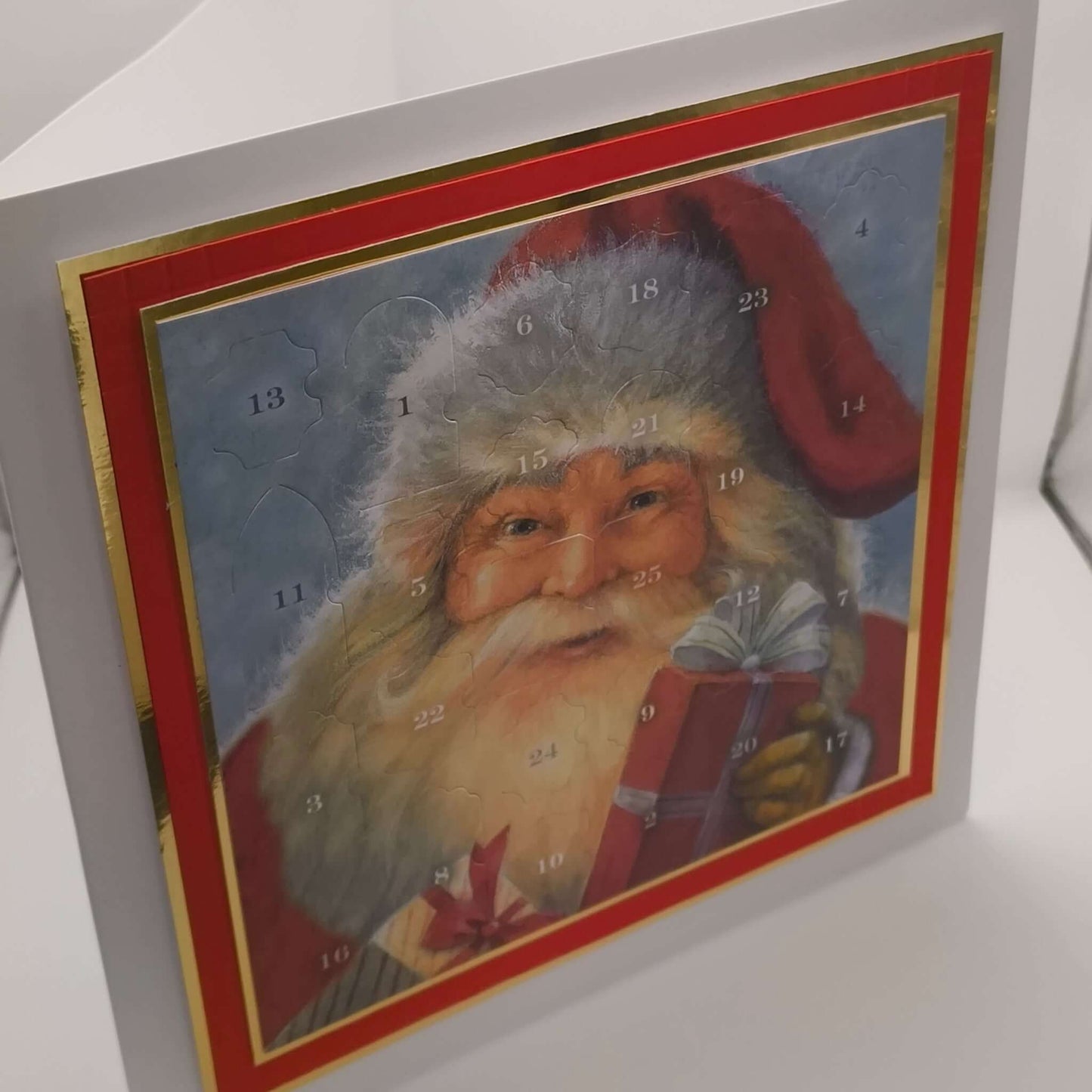 Vintage-style Santa Advent Calendar with red and gold border, photographed upright on a white background to show depth and card structure.