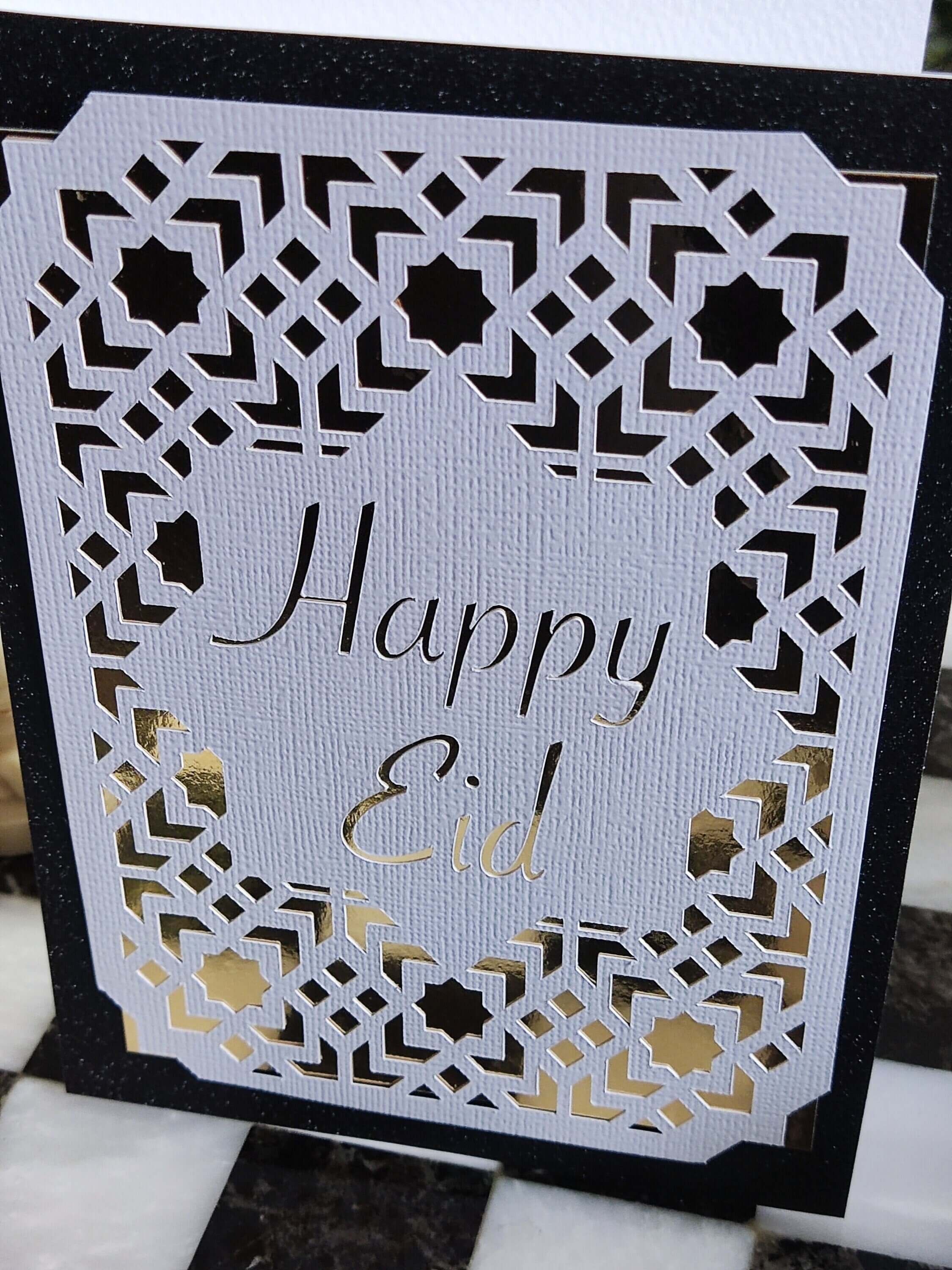 Happy Eid card featuring intricate laser cut Islamic geometric design in gold and black.